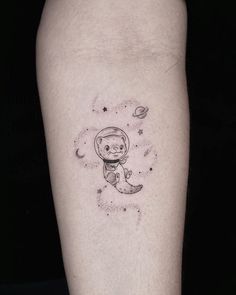 a small tattoo on the leg of a person with an astronaut bear and planets in the background