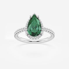 a pear shaped green diamond ring with diamonds on the sides and an oval halo around it