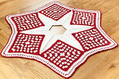 a red and white crocheted rug with a star on the center, sitting on a wooden floor