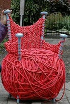 a woman kneeling down next to a red ball of yarn