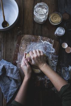 a person kneading dough on top of a wooden table