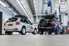 two suvs parked in a large building next to each other with their hood open