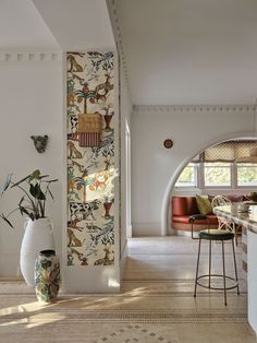 a large vase with plants in it sitting next to a wall covered in animal designs