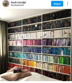 a bed sitting in front of a book shelf filled with books on top of it