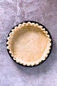 an uncooked pie crust sits in a black bowl on a gray table top