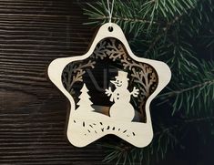 a wooden ornament with a snowman and trees in the center on a pine tree