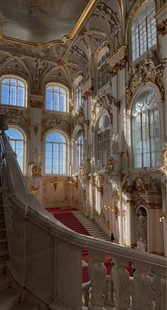 an ornately decorated staircase in a building with large windows and red carpeted stairs