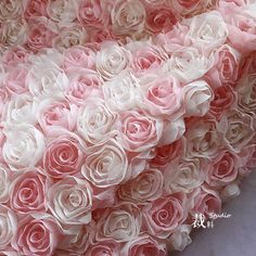 pink and white roses are arranged in the shape of a large rose on a bed