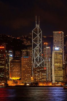 the city skyline is lit up at night, with skyscrapers in the foreground