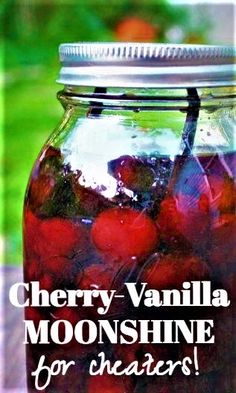 a jar filled with cherries sitting on top of a wooden table