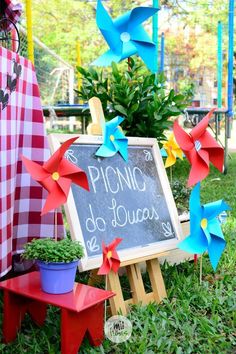 a chalkboard sign with pinwheels on it in front of some potted plants