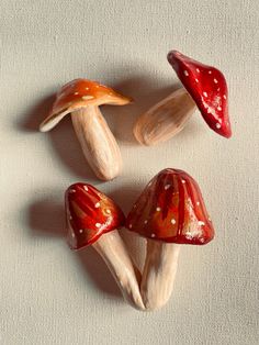 four red and white mushrooms sitting on top of a table