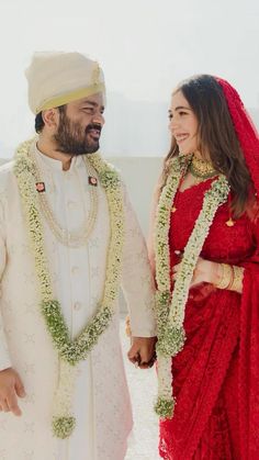 a man and woman standing next to each other in front of a white wall holding hands