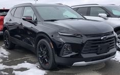 the front end of a black chevrolet suv parked in a lot with snow on the ground