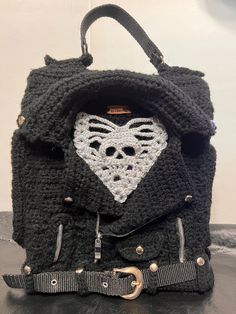 a black crocheted backpack with a white heart on it