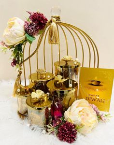 a birdcage filled with lots of flowers next to a card that says happy diwali