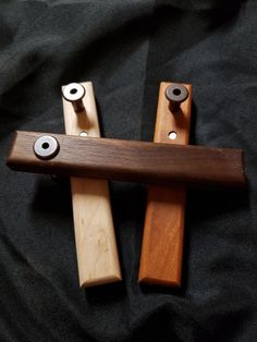 two pieces of wood sitting on top of a black cloth covered bed spread with eyeballs in the middle