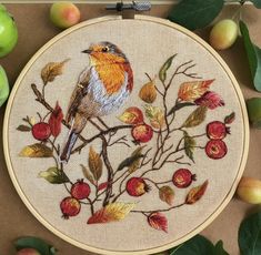 a bird is sitting on a branch with leaves and apples in front of the hoop