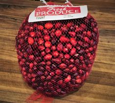 a red bag filled with lots of fruit on top of a wooden table