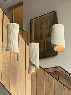 three lamps hanging from the side of a wooden wall next to a staircase with handrails