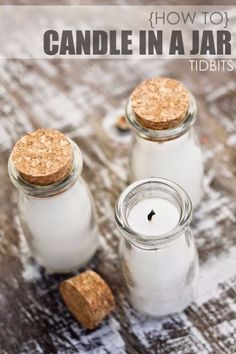 three jars filled with white candles sitting on top of a wooden table next to corks