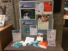 a bulletin board covered in pamphlets and papers on a wooden table next to a counter