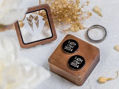 two wooden buttons are sitting next to each other on a white table cloth with flowers in the background