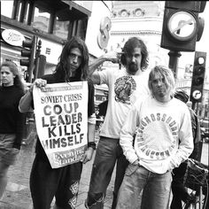 three men standing next to each other with signs on the street in front of them