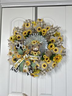 a wreath with sunflowers and a cow is hanging on the front door,