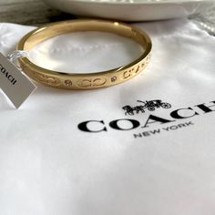 Nwt! Beautiful Authentic Coach Hinge Bangle Bracelet In Yellow Gold, With Delicate Rhinestones And “C” Logos. Very Elegant. An Accessory That Goes Well With Any Outfit. Brand New, Tags Attached. Opens Up For Easy On And Off. Comes With Coach Branded Retail Store Gift Box And Coach Branded/Logo Tissue Paper. Ready To Gift! - Hinge Closure - Insert Buckle Design Designer Plaque - Adjustable Push-Stud Fastening - 2.5” Diameter And 1/4” Width Approximately This Listing Includes: - New Coach Bracelet Branded Tissue Paper, Coach Bangle, Coach Jewelry, Coach Gift, Logo Gifts, Coach New York, Coach Gifts, White Jewelry, Hinged Bangle