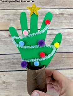 a hand made out of paper with a christmas tree on it and some pom poms