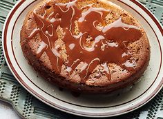 a chocolate cake with caramel drizzled on top sitting on a plate