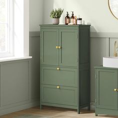 a bathroom with two green cabinets and a white sink in the corner next to a window