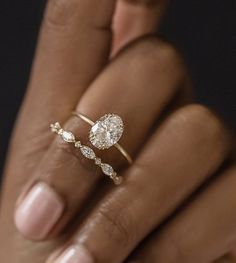 a woman's hand holding an engagement ring with two diamonds on the top and bottom