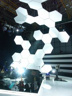 the lights are hanging from the ceiling in front of an array of hexagonal objects