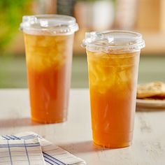 two plastic cups filled with liquid sitting on top of a table