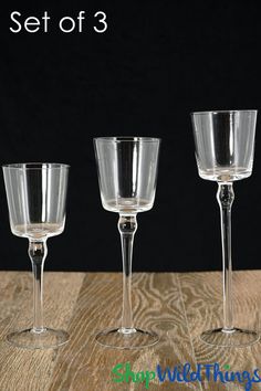 three empty wine glasses sitting on top of a wooden table with the words set of 3