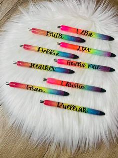 six pens with writing on them sitting on a fur covered surface, all in different colors