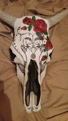 a cow skull with roses painted on it's face and antlers in the back