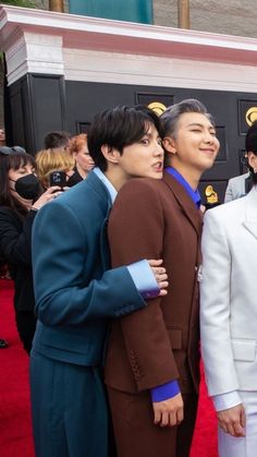 three men in suits posing for a photo on the red carpet