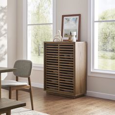 a wooden cabinet sitting next to a window in a room with hardwood floors and white walls