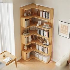 a wooden book shelf filled with books in a living room next to a white wall