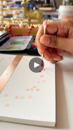 a person is holding a piece of paper with pink dots on it and writing something