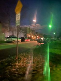 a street with cars parked on the side of it and green lights in the background