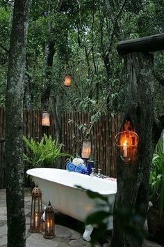 a white bath tub sitting next to a lush green forest