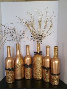 there are many bottles that have been decorated with gold glitter and black ribbon on them