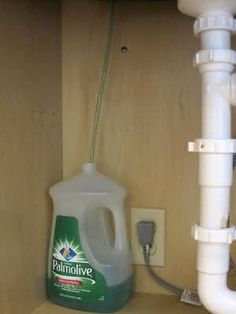 a bottle of liquid sitting on top of a counter next to a sink faucet