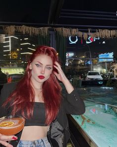 a woman with red hair holding a drink