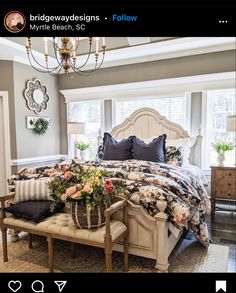 a bedroom with a large bed, chandelier and two windows in the room