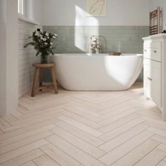 a bathroom with a white bathtub and wooden stool next to the tub in it